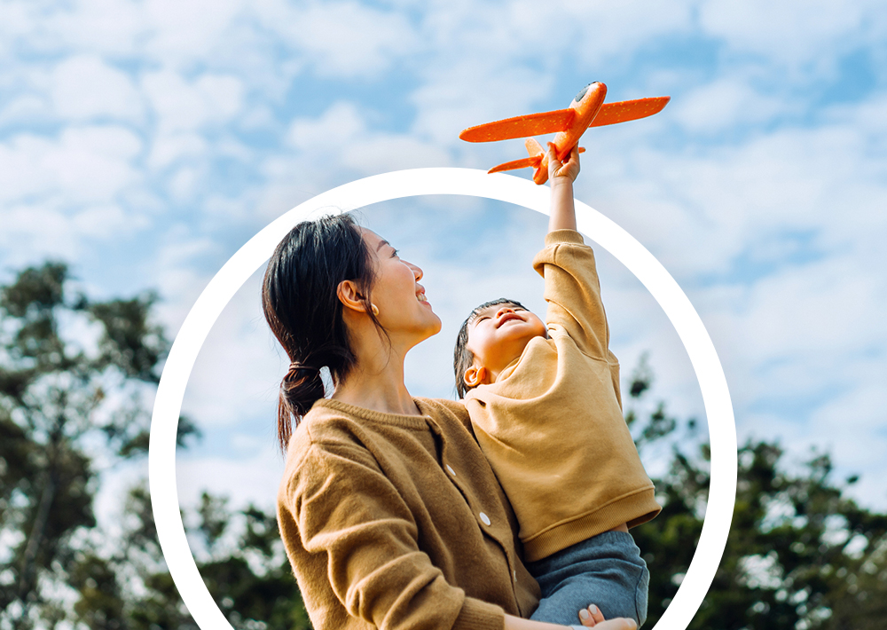 Mother and son holding a toy airplane and looking at the sky