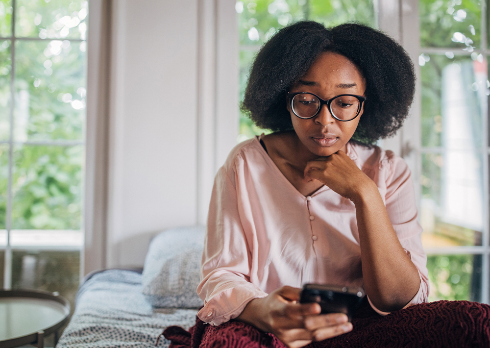Woman with concerned facial expression, looking at her phone